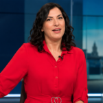 Yasmin Bodalbhai presenting the news in a modern TV studio, wearing a red dress.